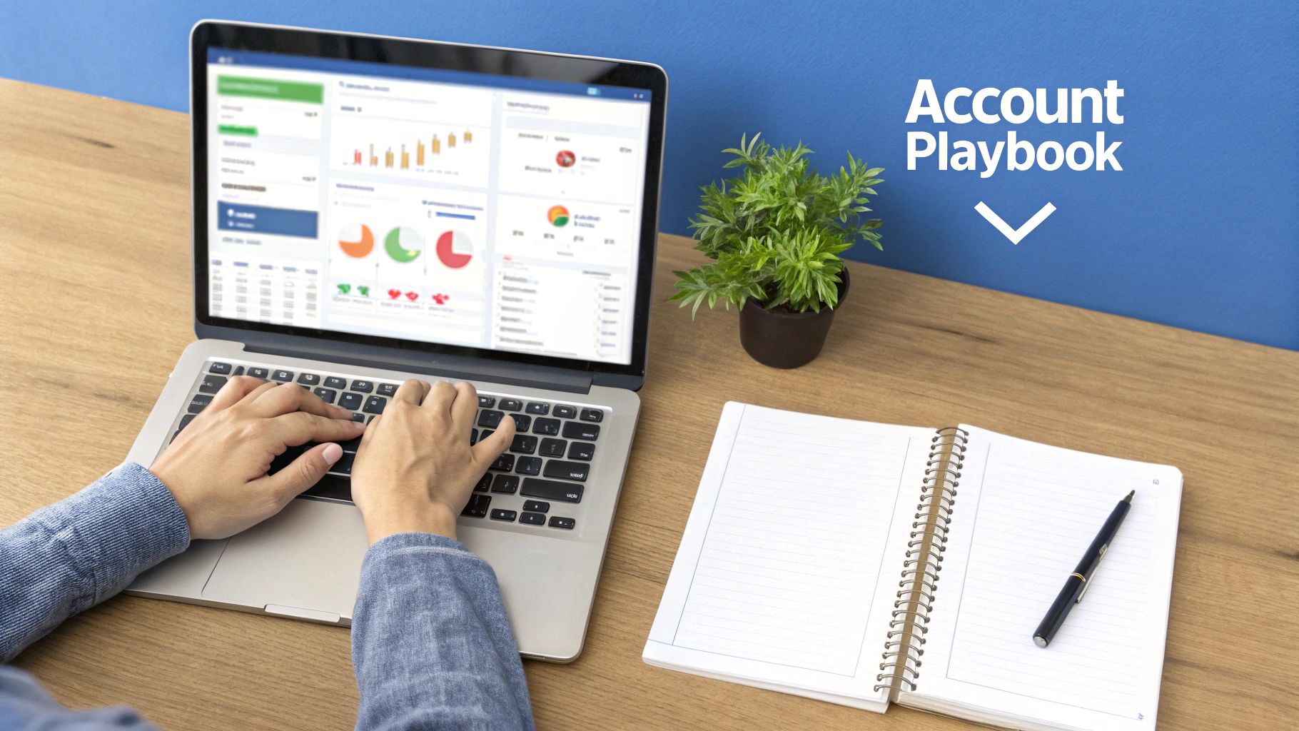 A person works on a laptop displaying data, with an open notebook and plant on a desk.