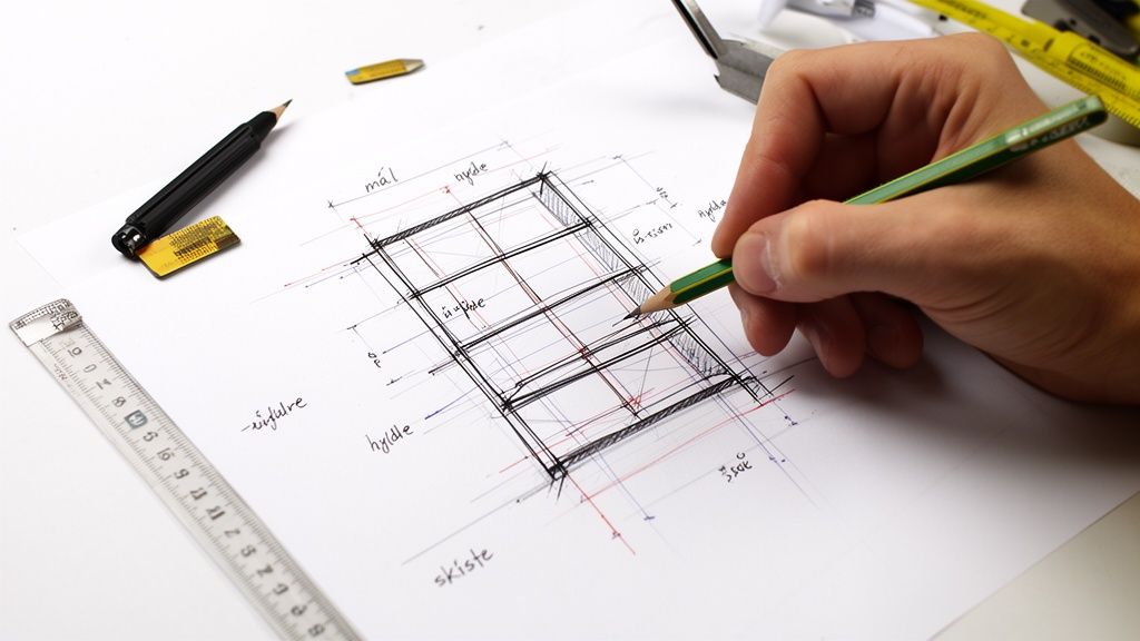 En hånd tegner en detaljeret skitse af en reol på et stykke papir med blyant og lineal.