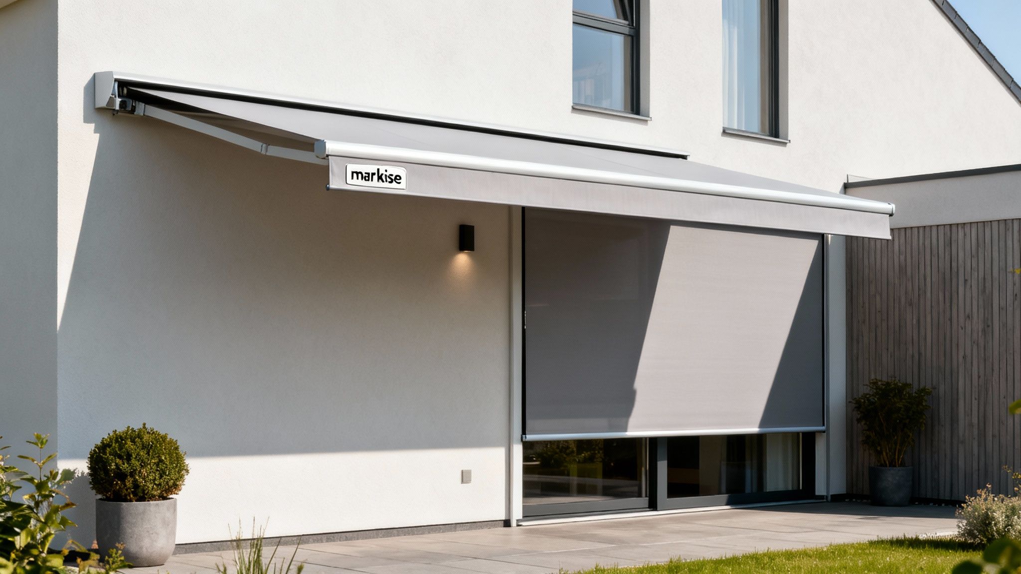 En moderne hvid bygning med en udslået grå markise og en vertikal screen, der dækker vinduet på terrassen.
