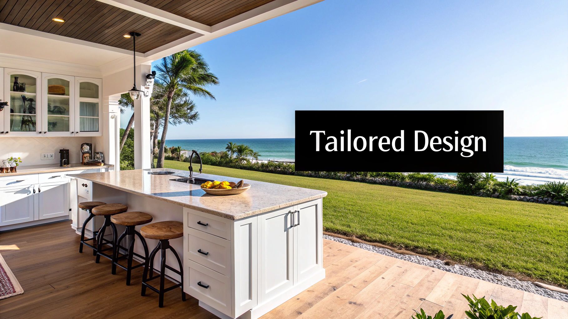 Luxurious outdoor kitchen featuring white cabinetry, a large island, and bar stools, with an ocean view.