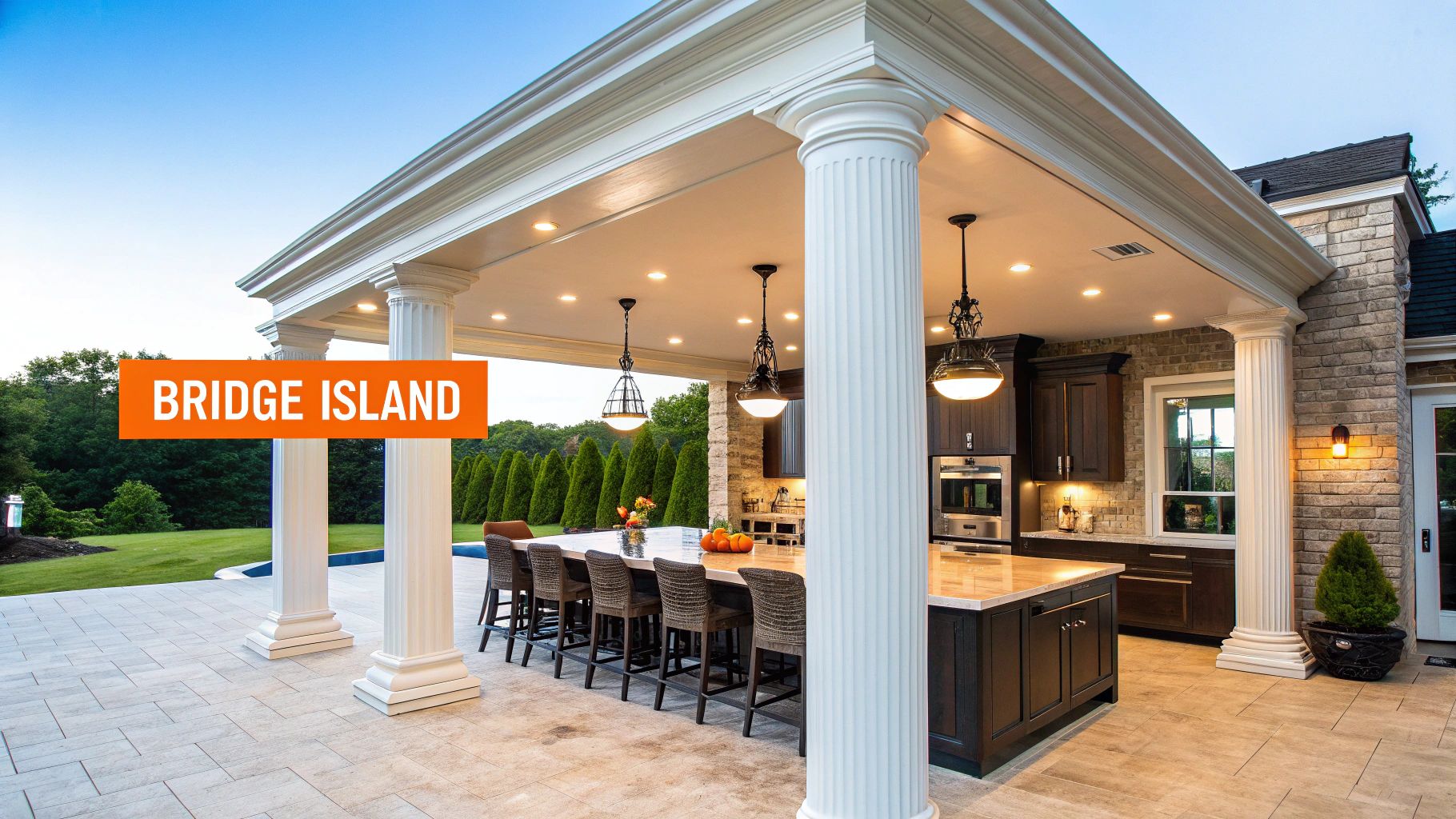 Luxurious outdoor kitchen featuring a large island, ample bar seating, and classical columns under a covered patio.