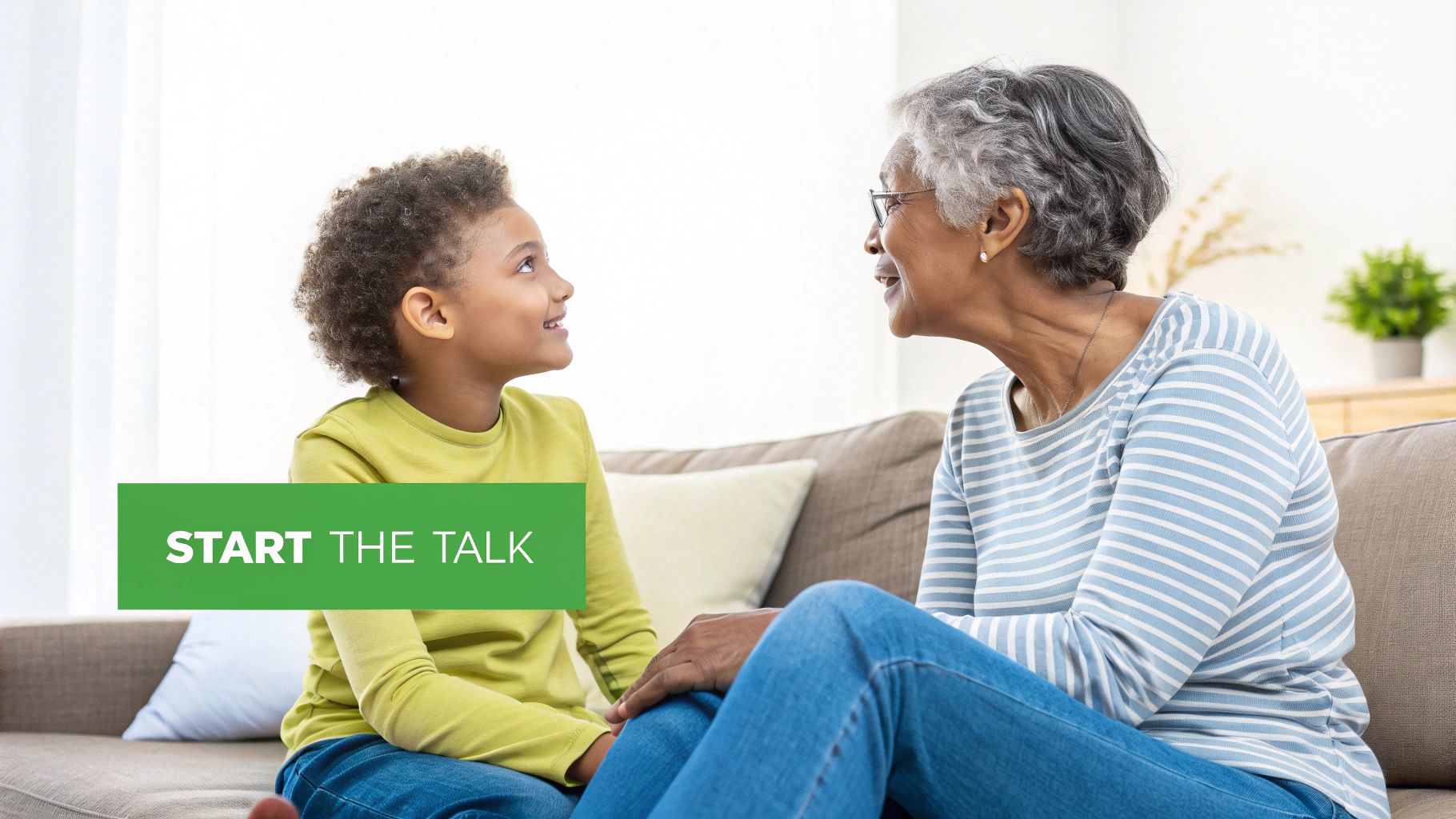 A grandmother and grandson smiling and engaging in conversation on a living room sofa