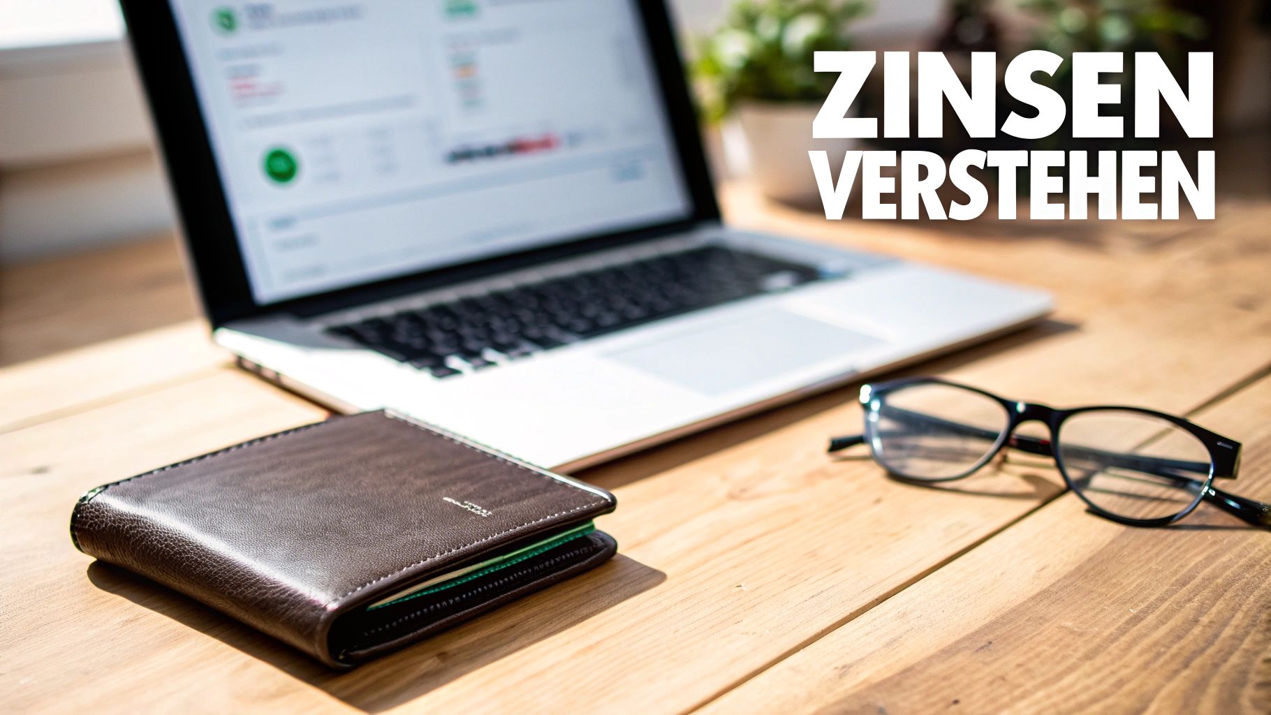 Laptop, Geldbörse und Brille auf einem Holztisch mit dem Text 'Zinsen verstehen'.