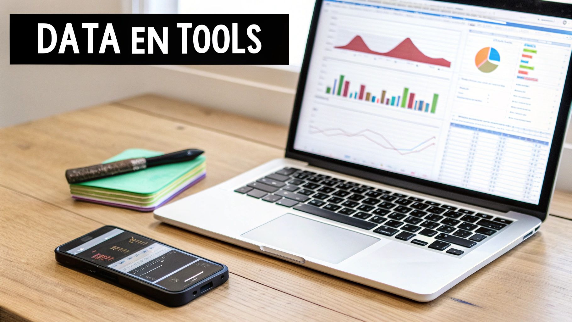 Een laptop toont data en grafieken naast een smartphone, notitieblokken en een pen op een houten bureau.