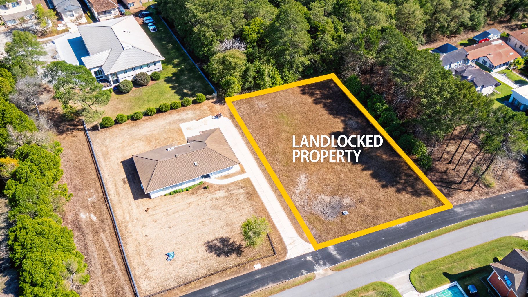 Drone shot highlighting a landlocked property in yellow, adjacent to residential homes and a street.