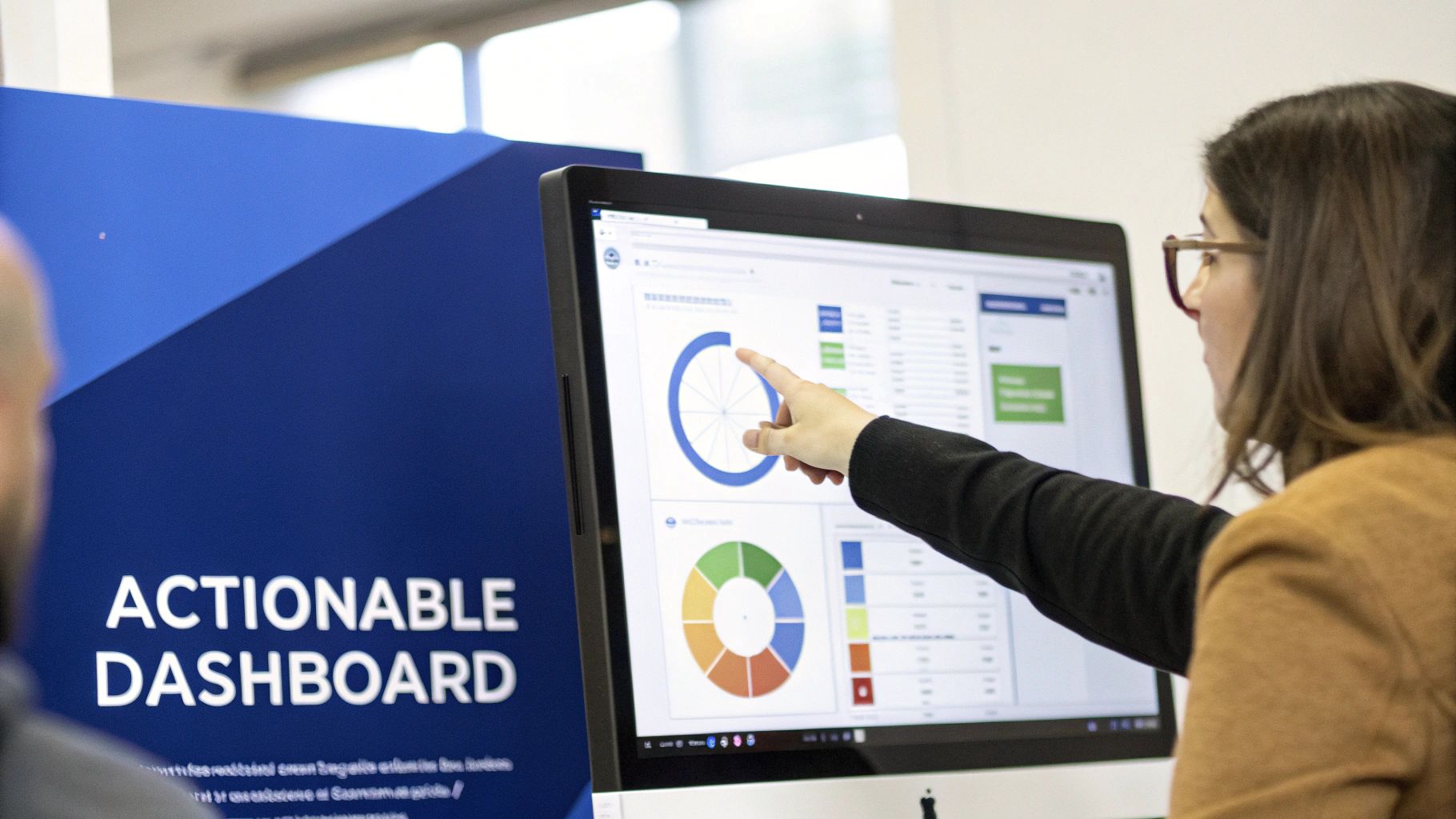 Woman points at a computer screen displaying an actionable dashboard with data visualizations during a business meeting.