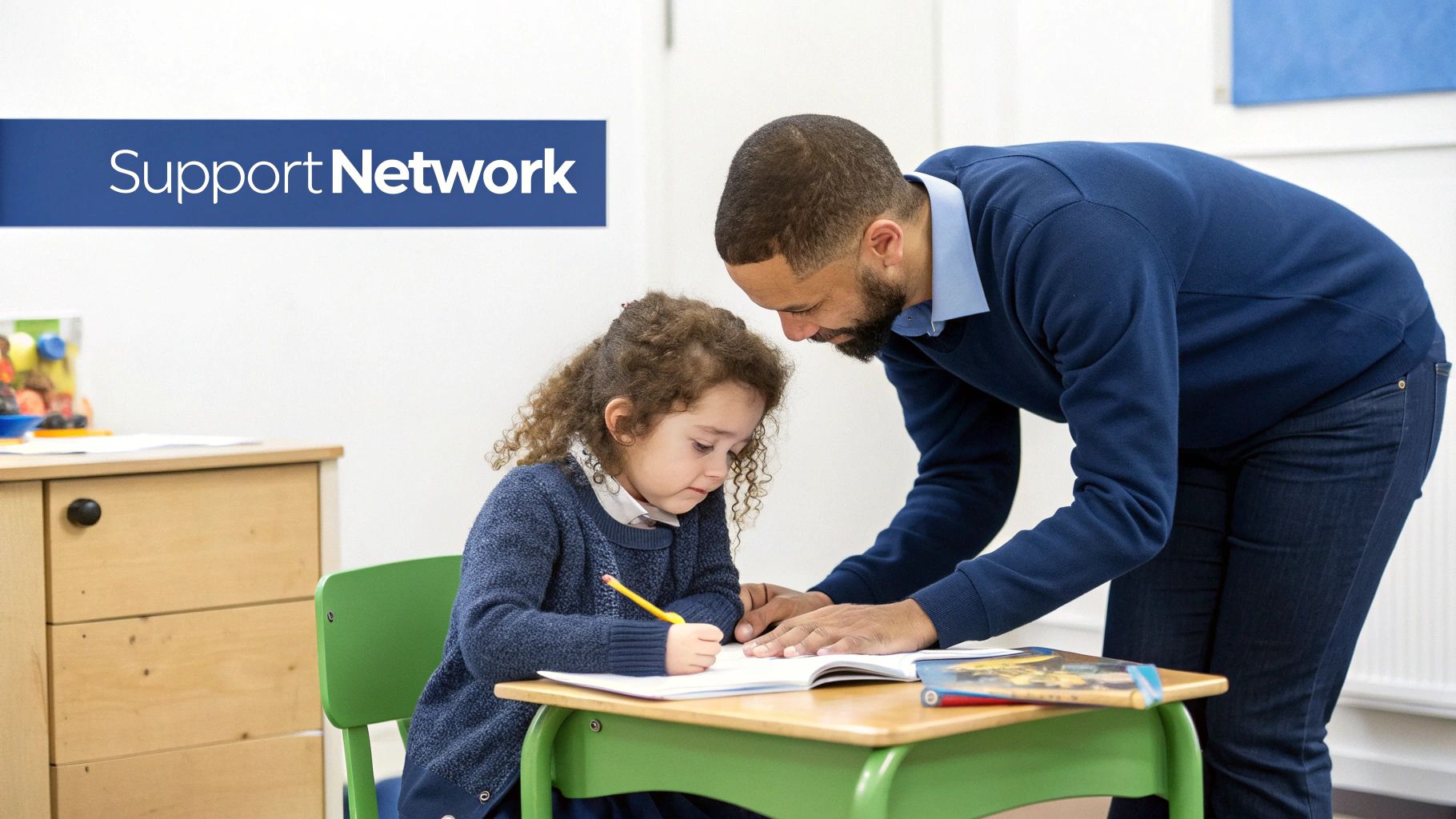 An adult male assists a young girl with curly hair writing in a notebook, symbolizing support.