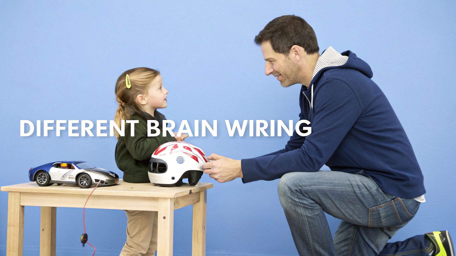 A father gives a helmet to his young daughter, with a toy car on a table and text 'Different Brain Wiring'.
