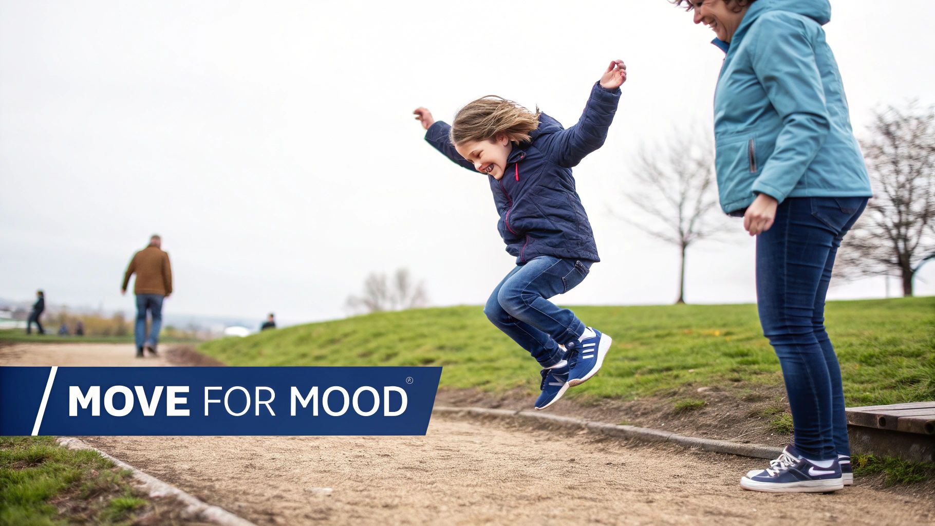 A happy child jumps in the air with a smiling adult nearby on an outdoor path.