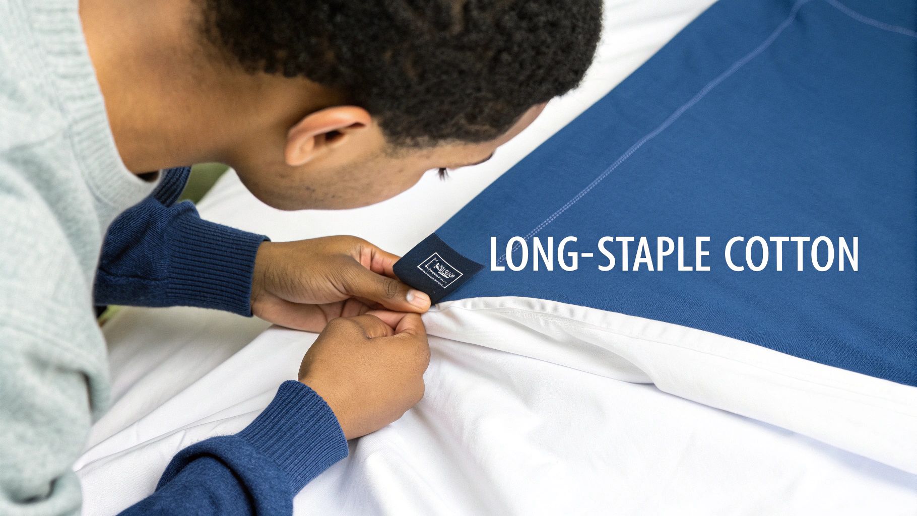 A person carefully inspects a 'LONG-STAPLE COTTON' label on luxurious blue bedding.