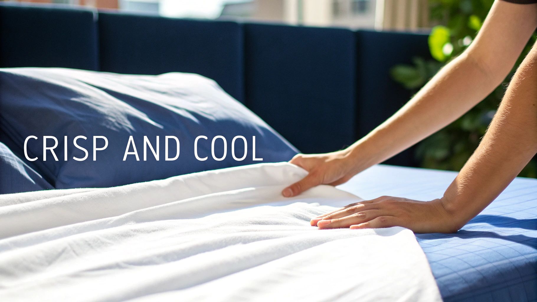 Hands making a bed with crisp white sheets and blue bedding, emphasizing a cool and fresh feel.