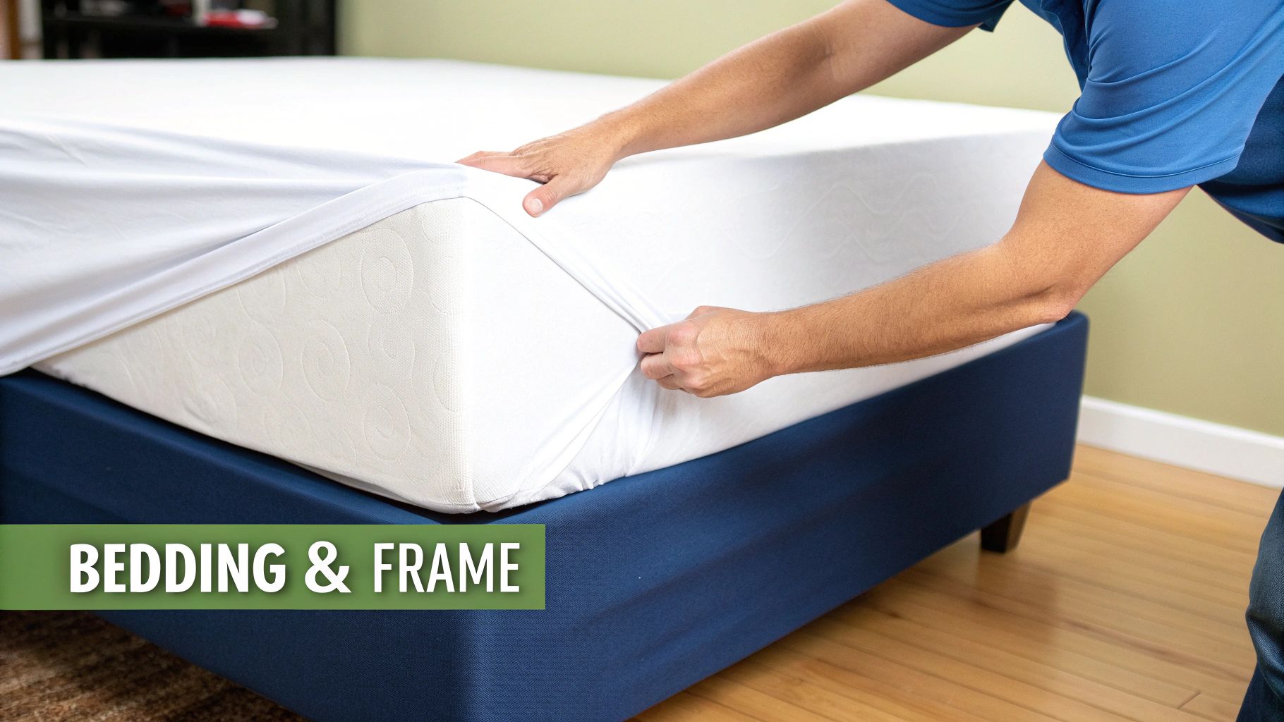 A person's hands pull a white fitted sheet over a mattress on a dark blue bed frame.