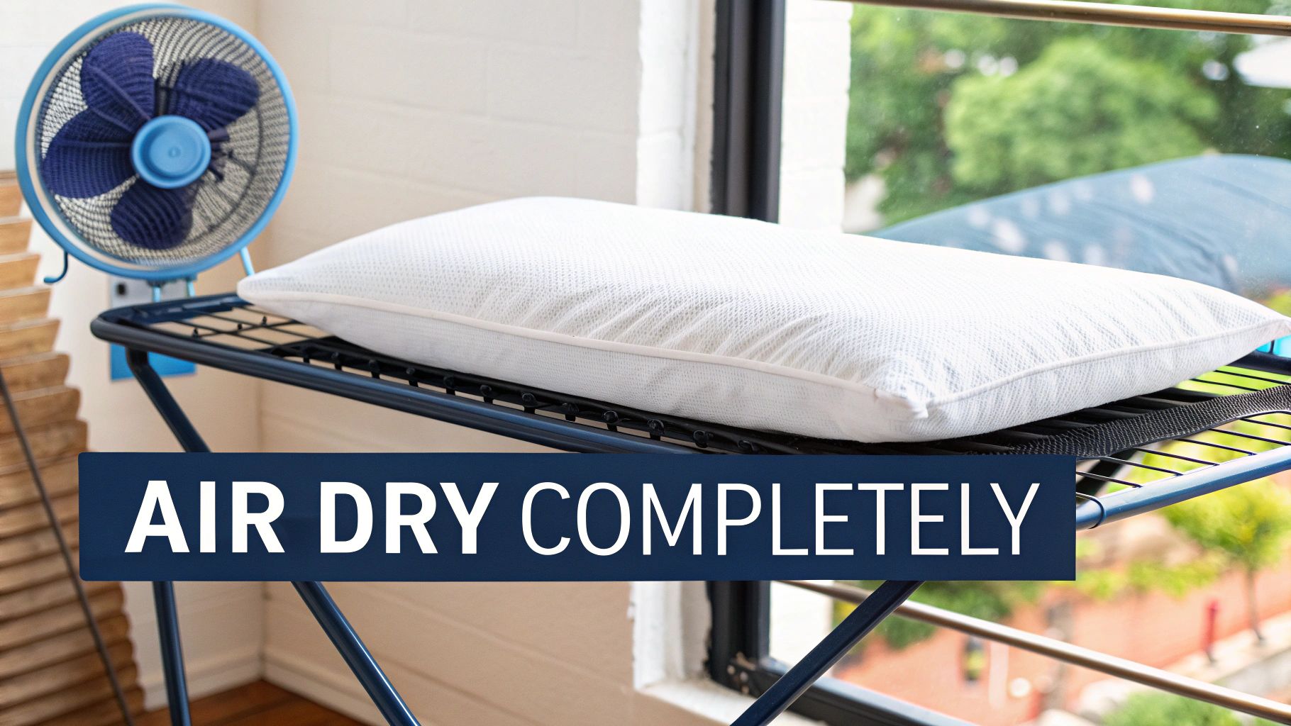 A white memory foam pillow air drying on a laundry rack with a blue fan for ventilation.
