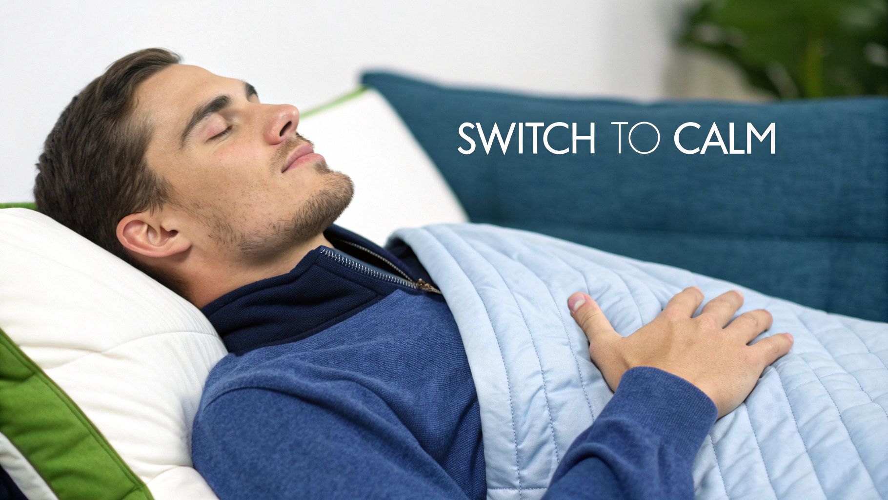 A man sleeps peacefully on a couch, covered by a blue weighted blanket, promoting calm.