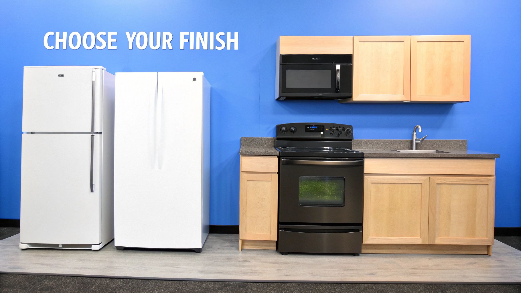 Two white refrigerators, a black microwave, a range, and light wood kitchen cabinets.