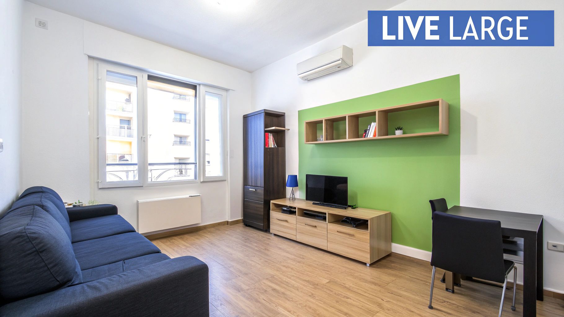 Bright, modern living room with large windows, light-colored furniture, and well-organized shelving, demonstrating effective small space design.