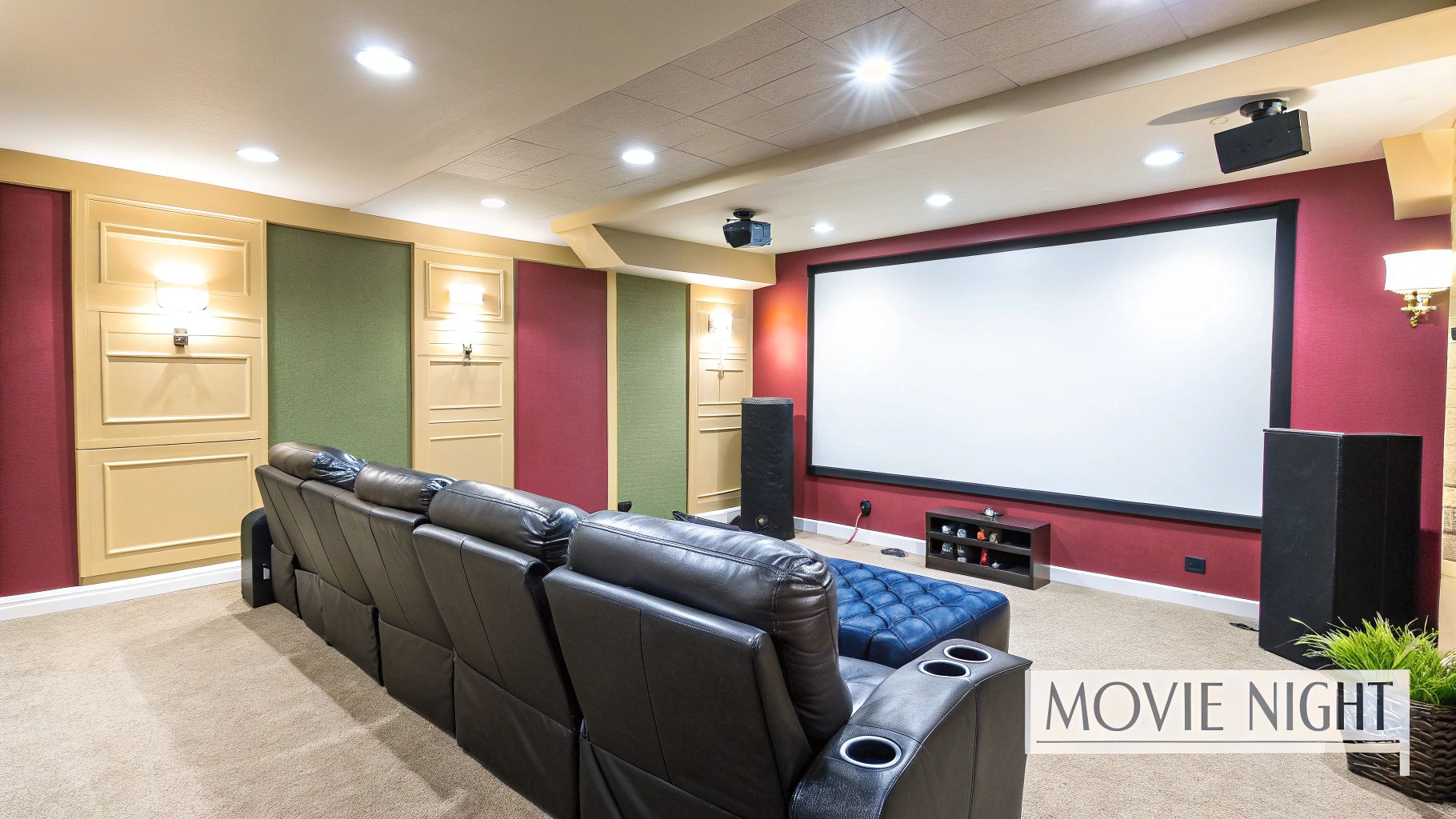 A luxurious basement home theater with a large screen, black recliners, and accent lighting.