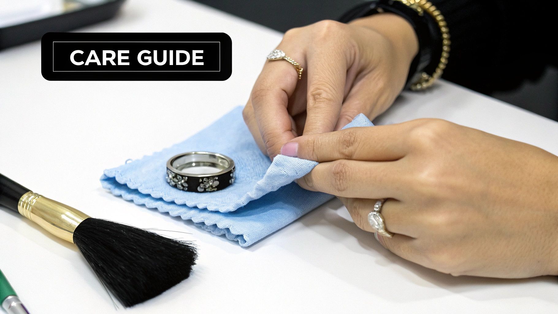Close-up of hands cleaning a ring with a blue cloth, next to a brush and another ring, under a 'CARE GUIDE' label.