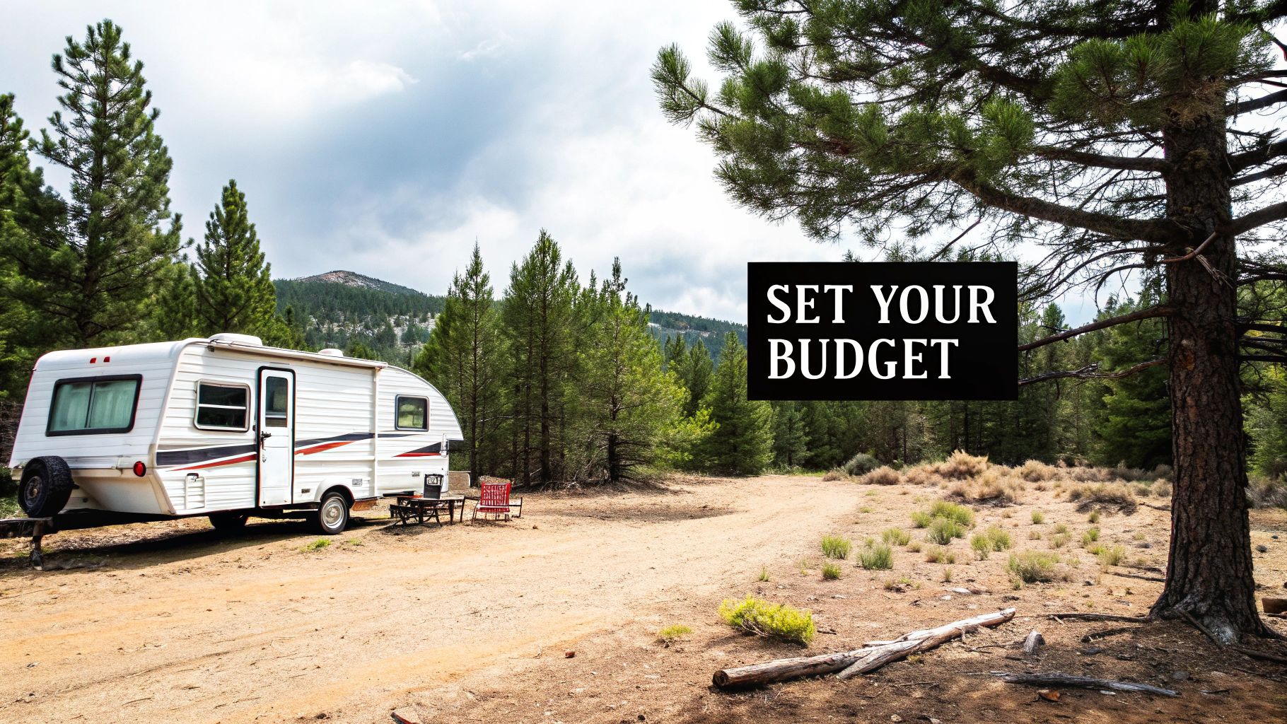 A travel trailer parked in a serene forest setting with a lake in the background.