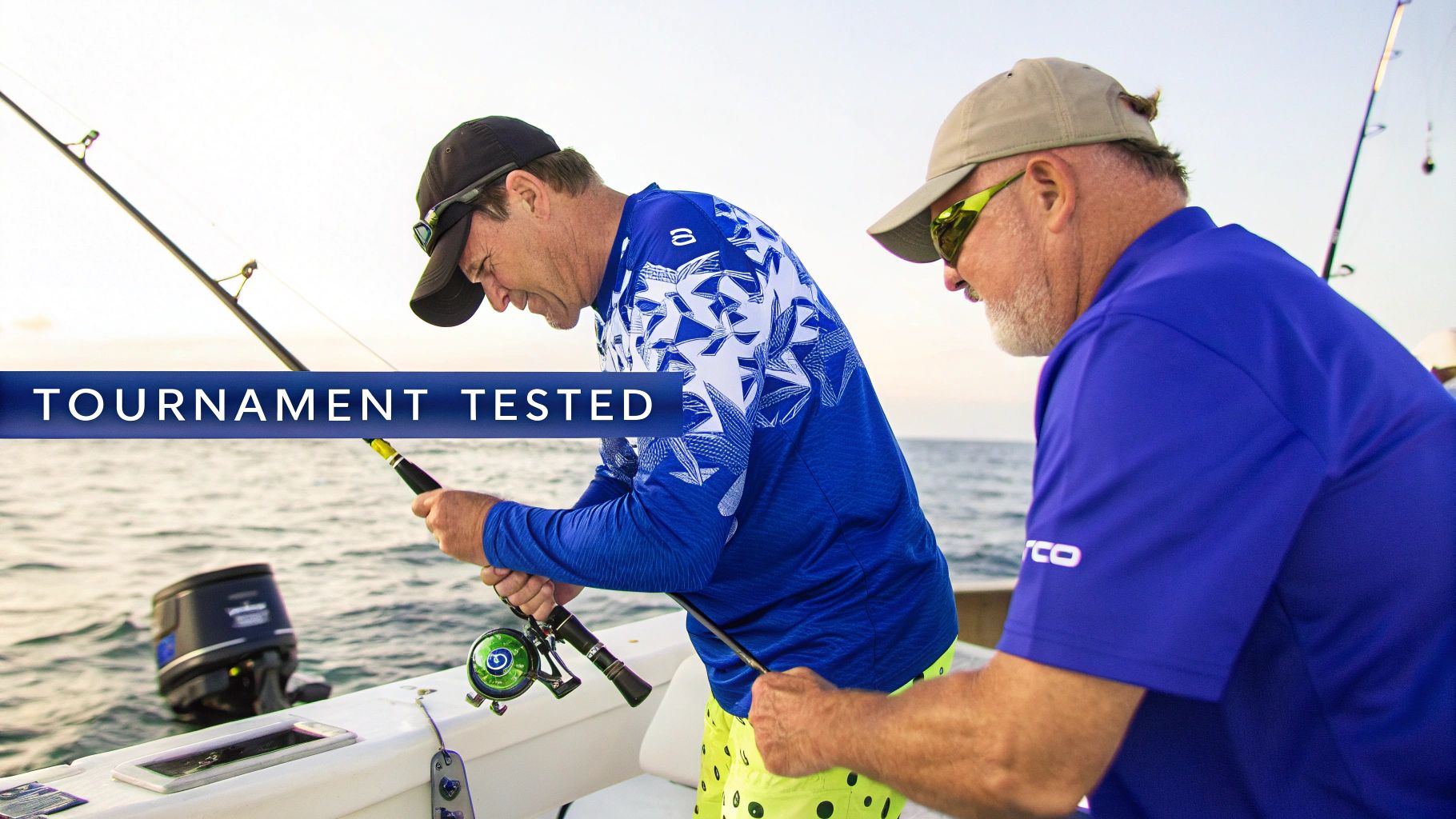 Two men on a boat, one holding a fishing rod, with a "Tournament Tested" banner.