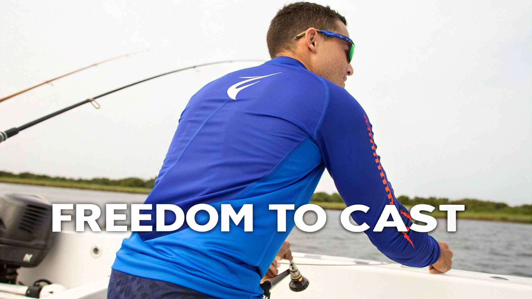 A man in a blue long-sleeve fishing shirt and sunglasses on a boat, facing the water with fishing rods.
