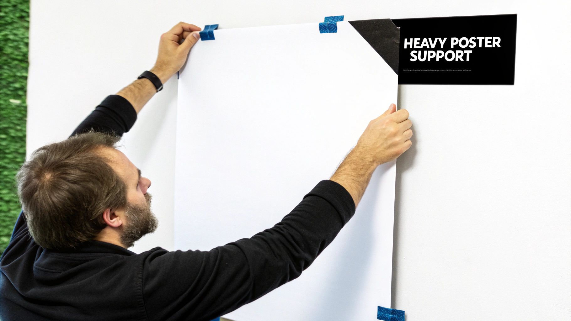 A person hanging a poster using a wooden magnetic poster hanger.