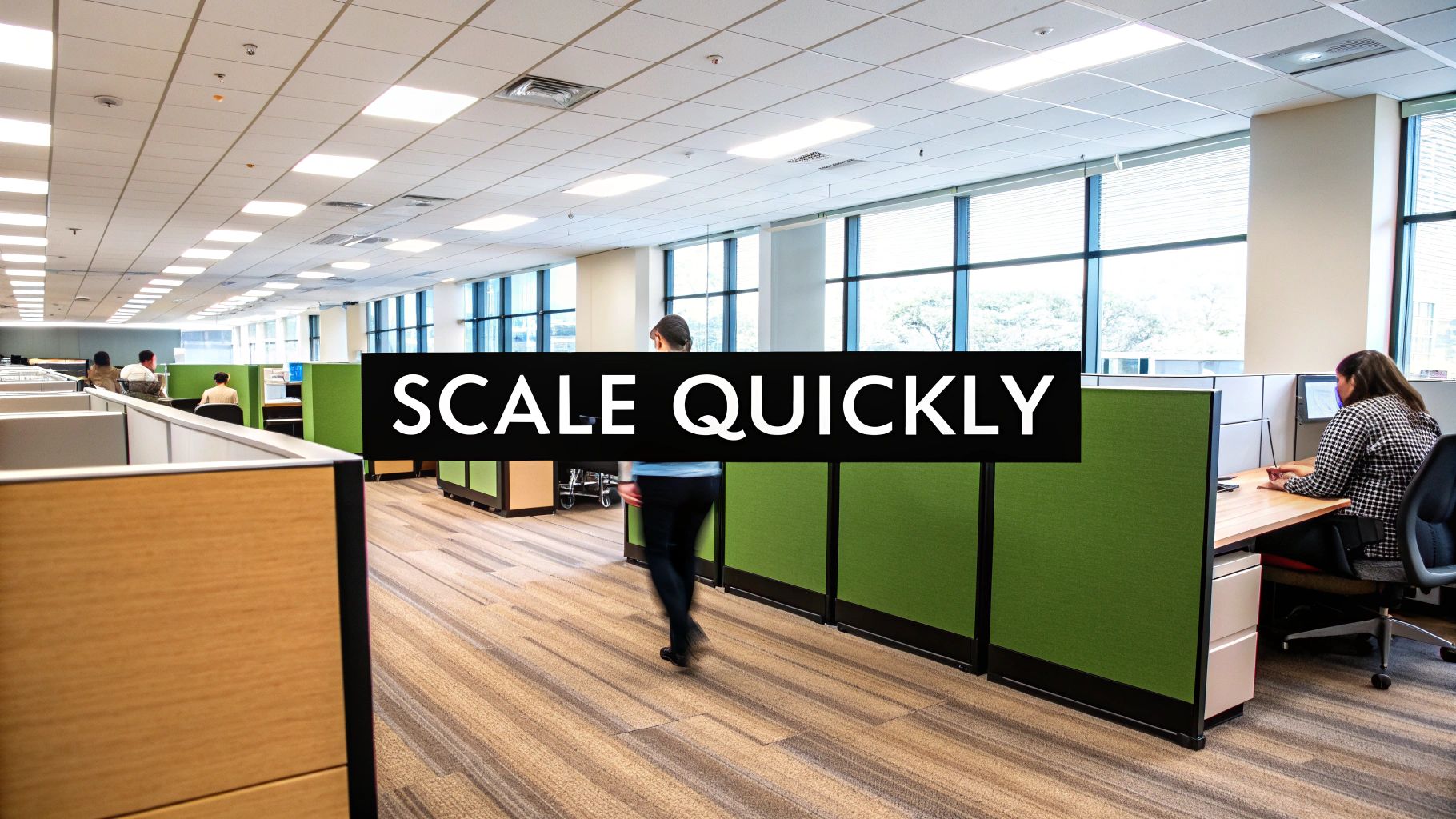 An open-plan office with cubicles and people working, illustrating the message 'SCALE QUICKLY' for business growth.