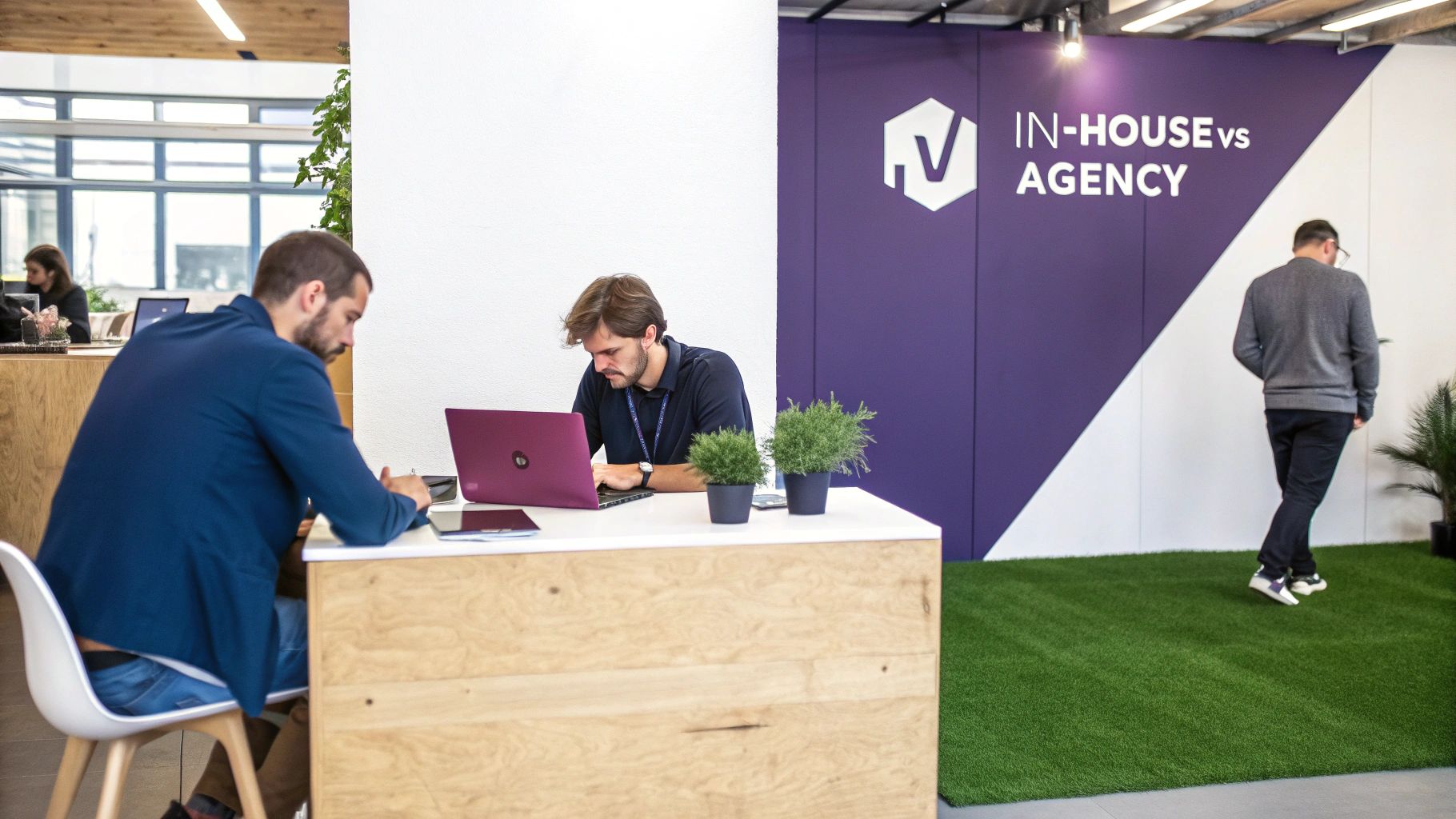 People working on laptops in a modern office, next to a wall with 'IN-HOUSE vs AGENCY' branding.