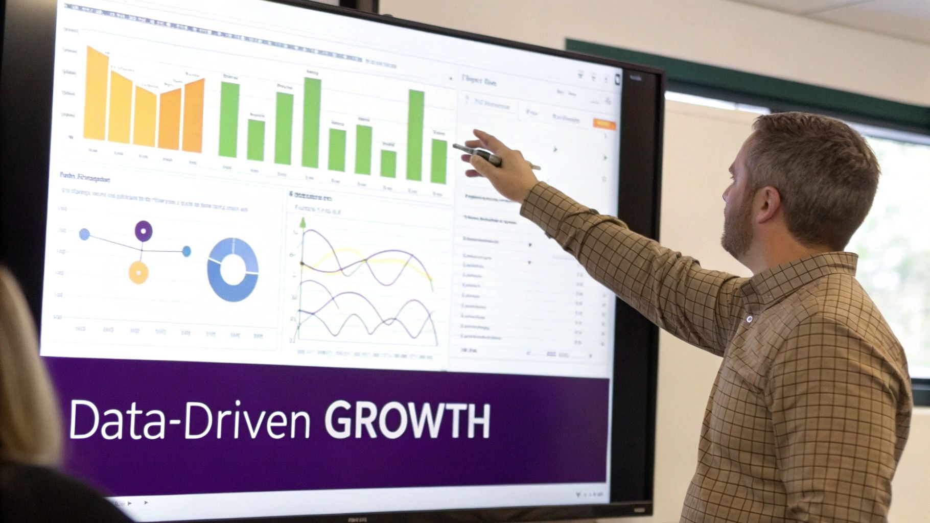 Man pointing at a large screen displaying various data charts and 'Data-Driven GROWTH'.