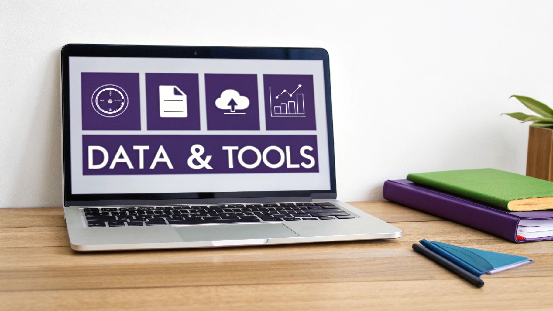 A laptop screen displays 'DATA & TOOLS' with icons, placed on a wooden desk with books and a pen.