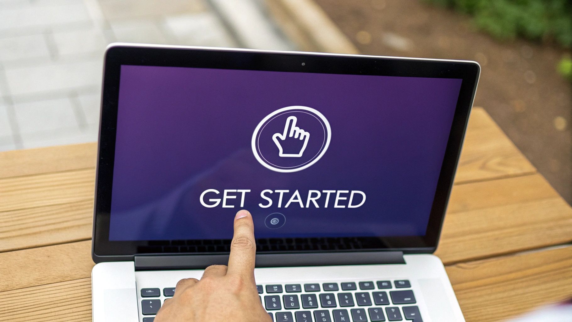 A hand taps a laptop screen displaying a 'GET STARTED' button and a pointer icon.