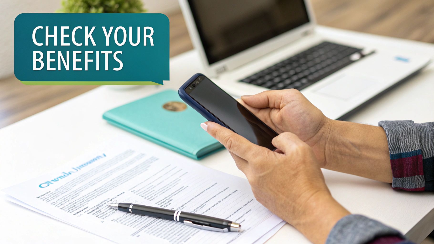 A person uses a smartphone to check their benefits online, with documents and a laptop on a desk.