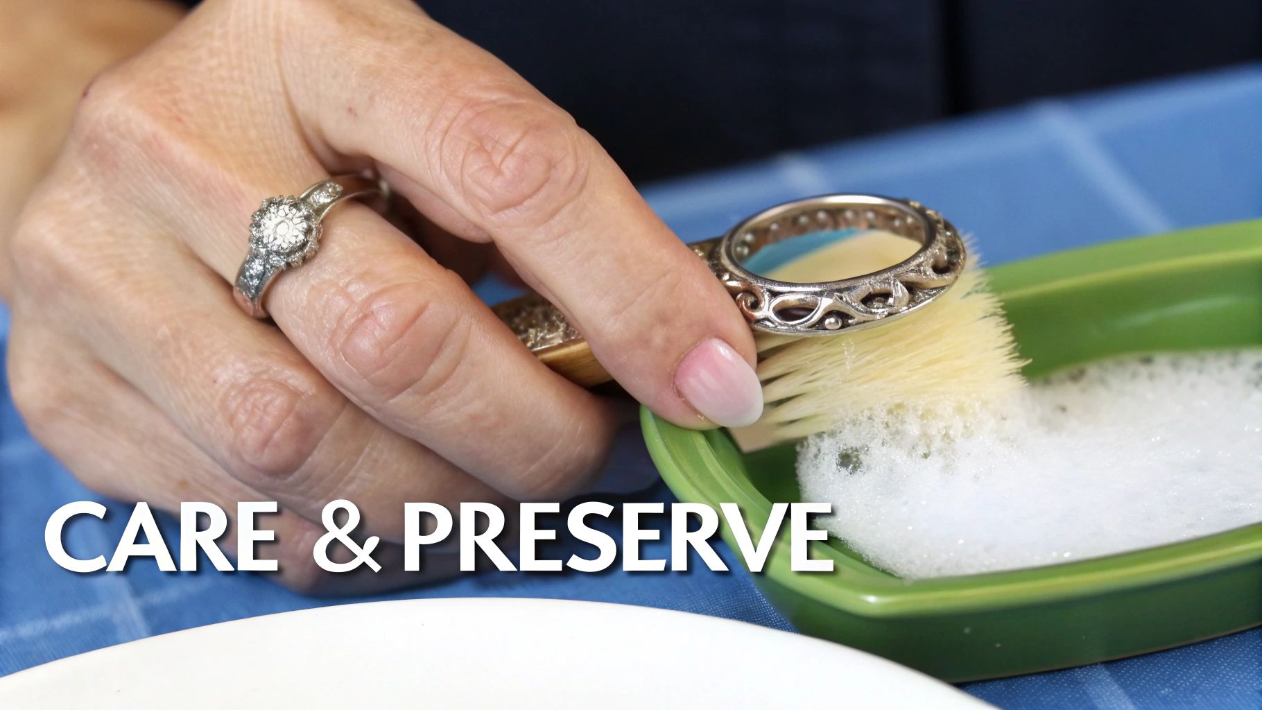 A soft cloth gently polishing an antique platinum wedding ring, with a small bowl of soapy water nearby.