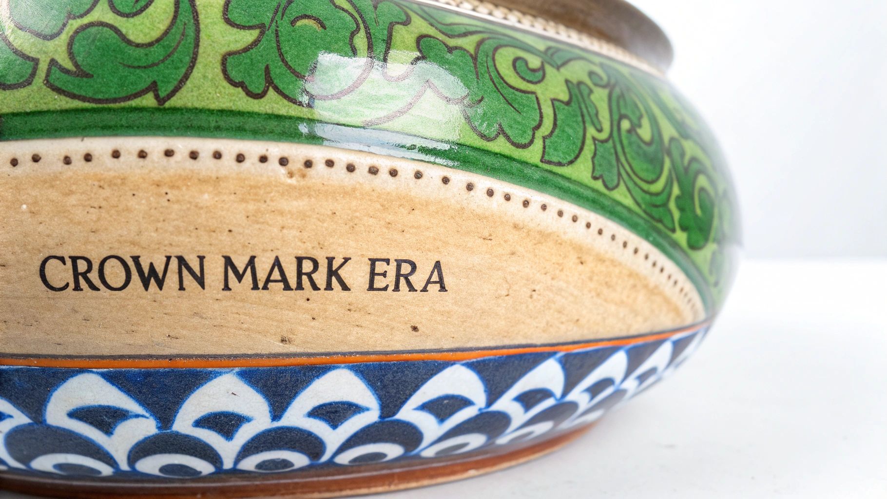 Decorative ceramic bowl base showing Crown Mark Era text with green floral and blue wave patterns