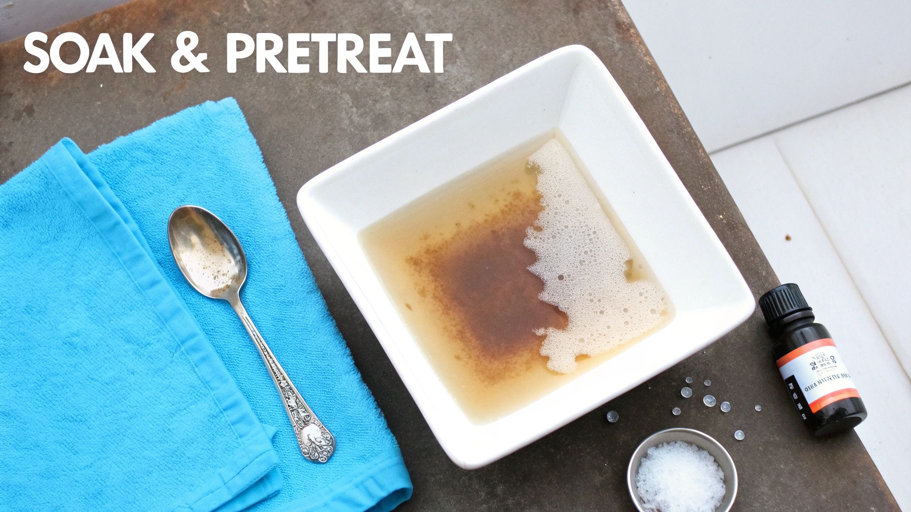 A blue towel, dirty spoon, and bowl with pre-treatment soak and essential oil, labeled 'SOAK & PRETREAT'.
