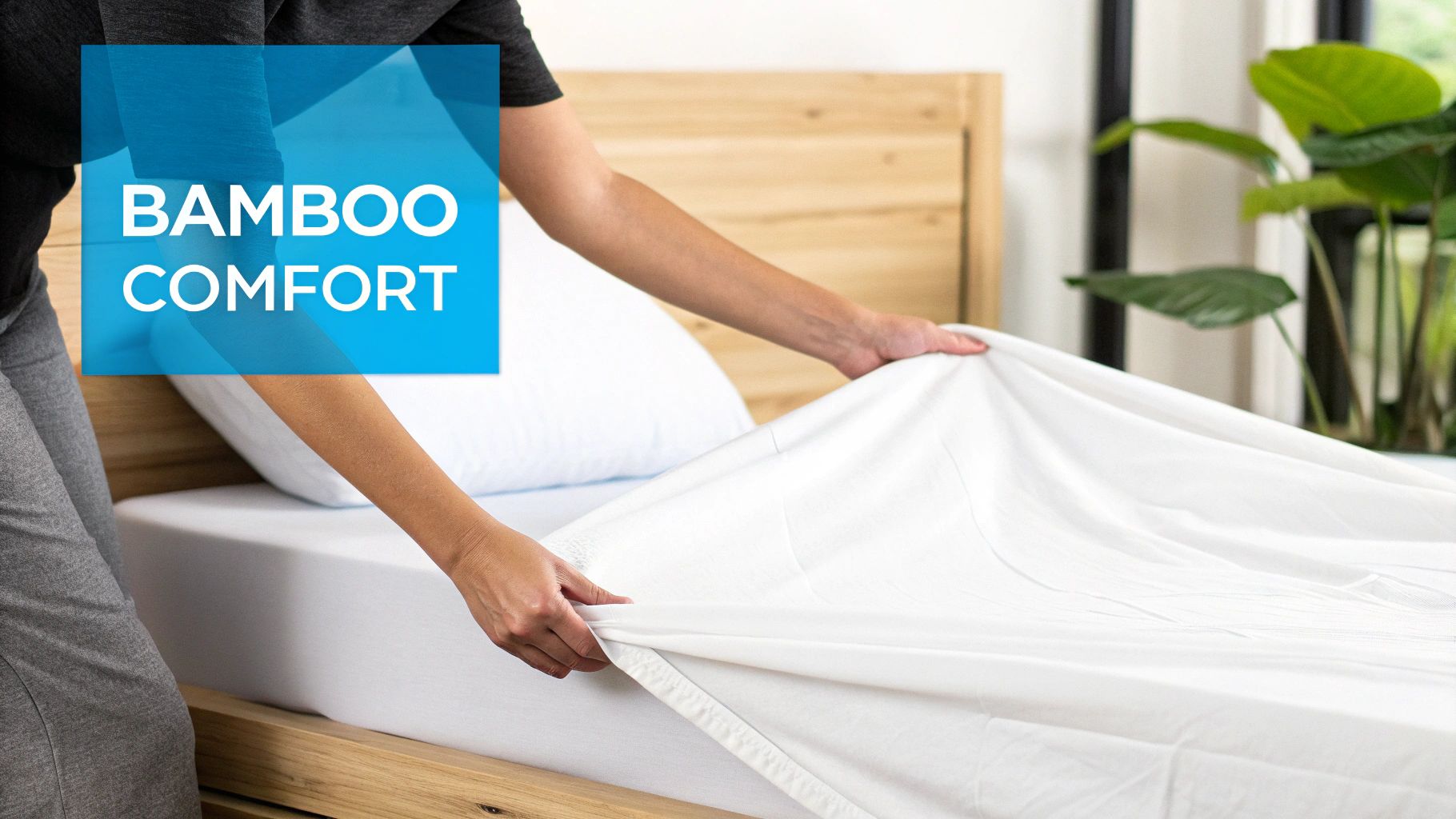 A person's hands are placing a white fitted sheet on a bed with a wooden frame.