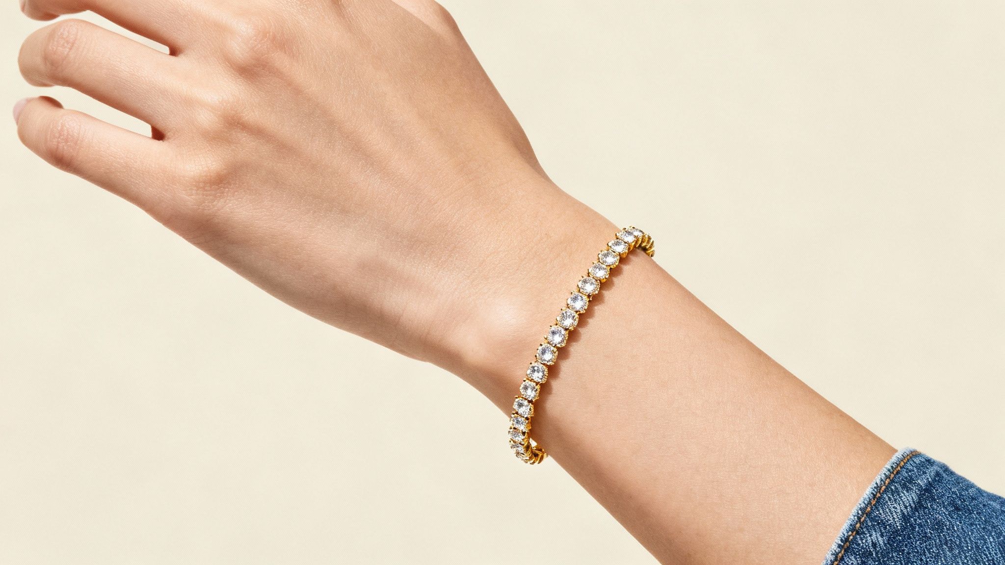 A close-up of a sparkling diamond tennis bracelet on a textured background.