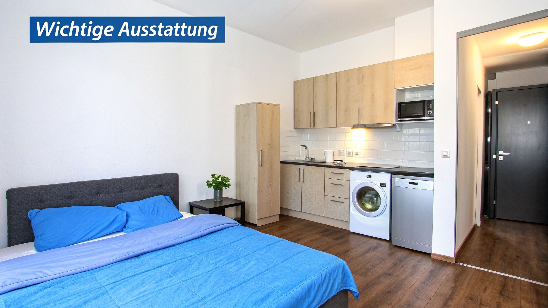 Ein möbliertes Studio-Apartment mit Bett, moderner Küchenzeile, Waschmaschine und Holzboden.