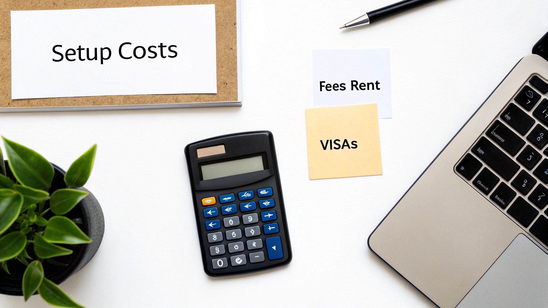 Calculator and laptop on desk with setup costs and visa fees notes for business planning