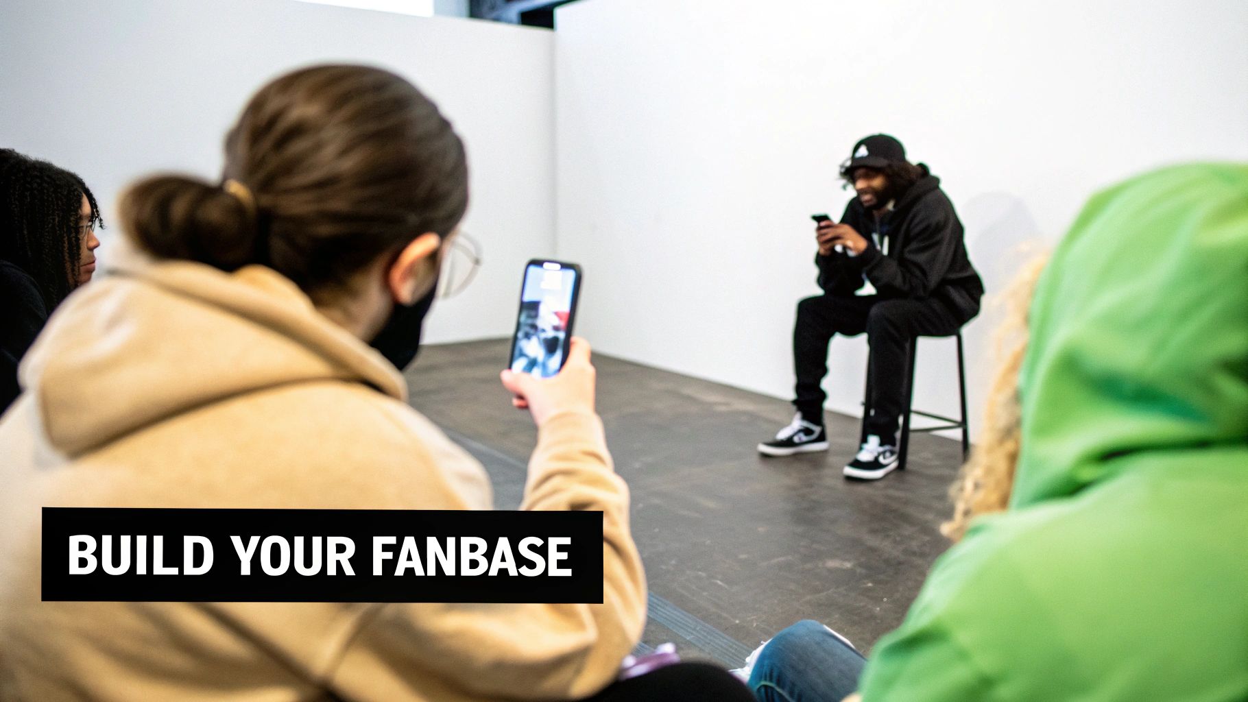 A person records an artist on a phone, with others observing, highlighting content creation to build a fanbase.