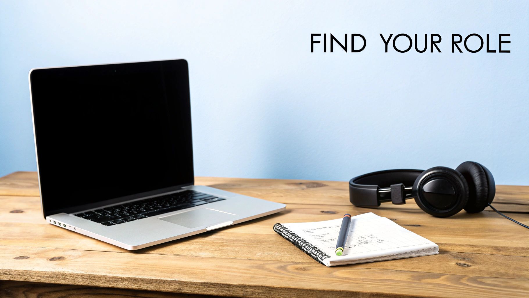 A laptop, headphones, notebook, and pen on a wooden desk with 'FIND YOUR ROLE' text.