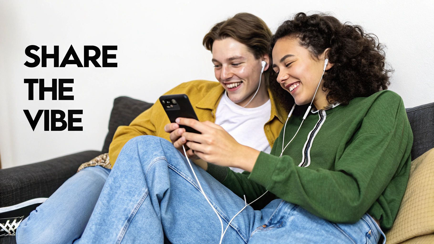 Two people happily sharing music on their phones while wearing headphones
