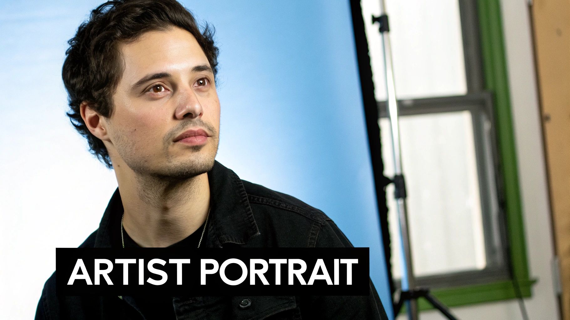 Artist portrait of a man with dark hair in a black denim jacket looking to the side.
