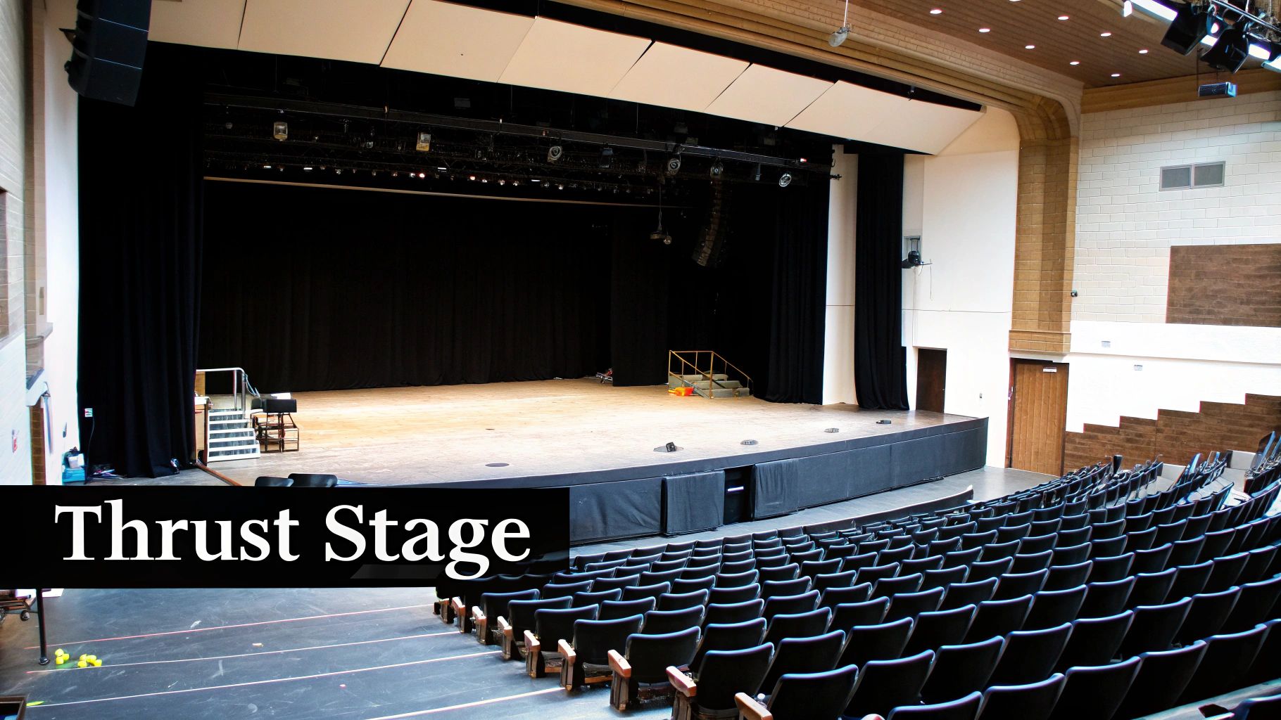 Modern thrust stage with black curtains, wooden floor, and rows of auditorium seating