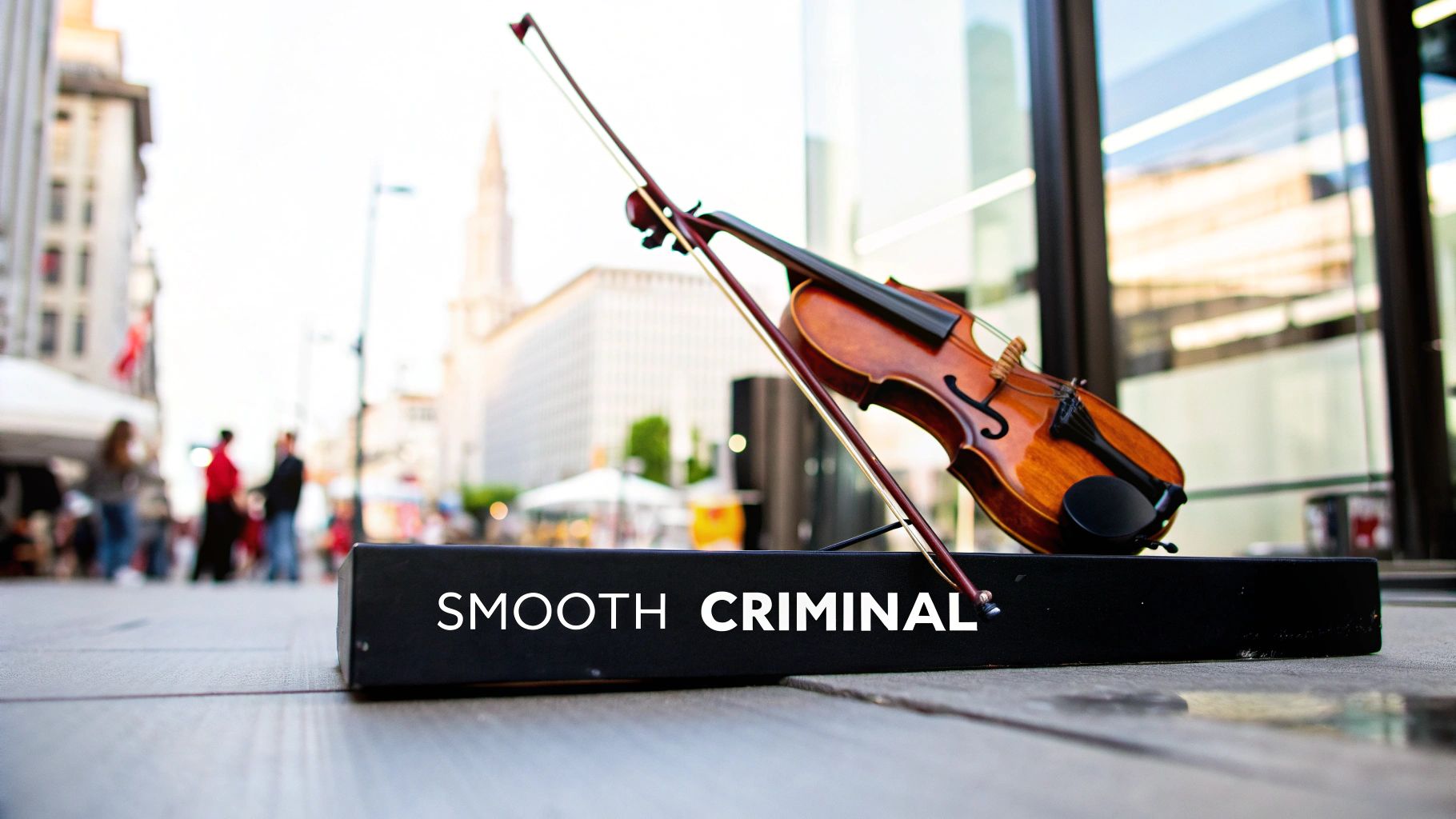 A brown violin and bow rest on a black stand reading "SMOOTH CRIMINAL" on an urban street.