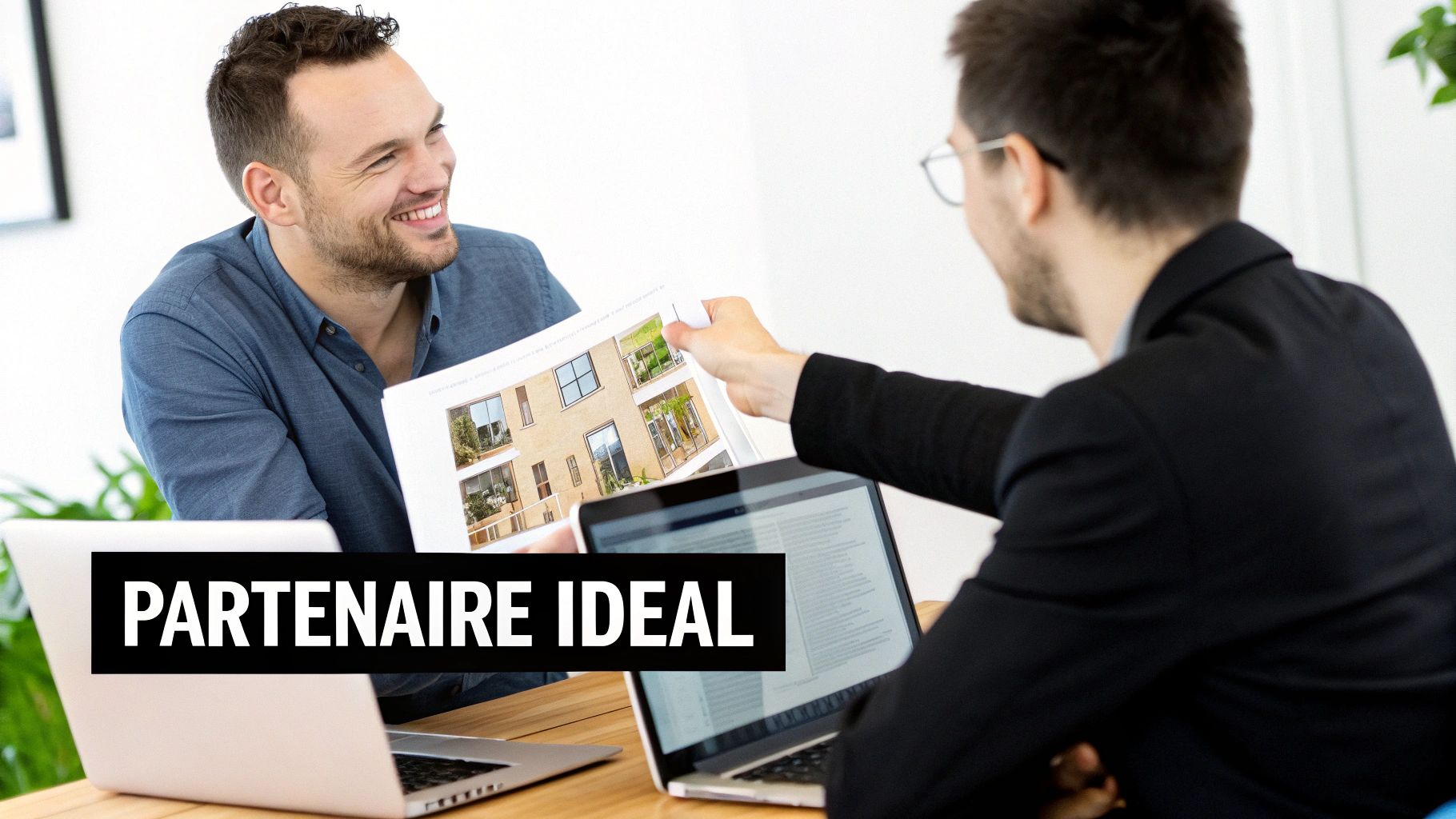 Deux hommes d'affaires souriants discutent lors d'une réunion, l'un présentant des plans de bâtiment à l'autre, symbolisant un partenariat idéal.
