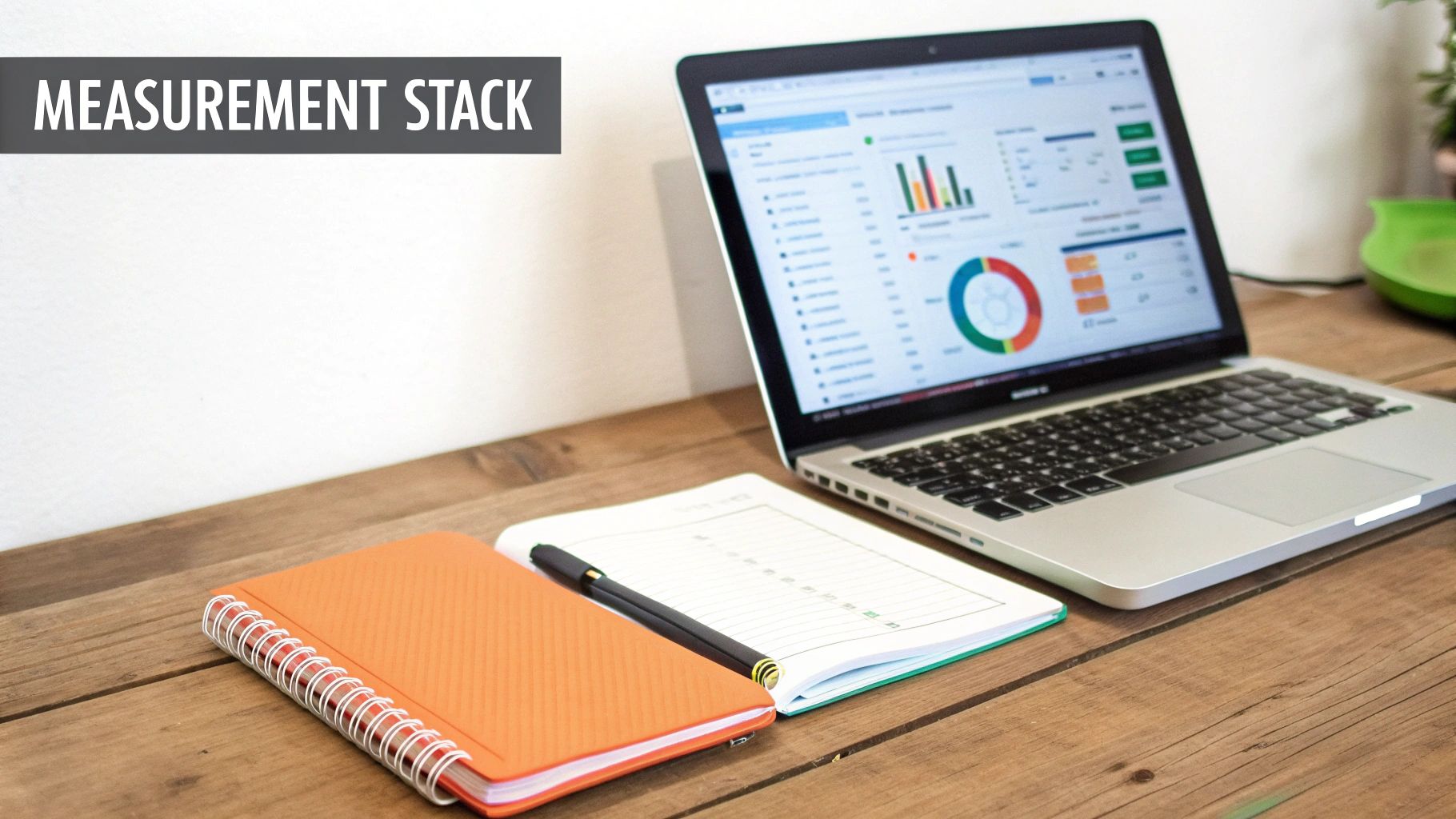 A laptop displaying data visualizations, charts, and graphs, with notebooks and a pen on a wooden desk.