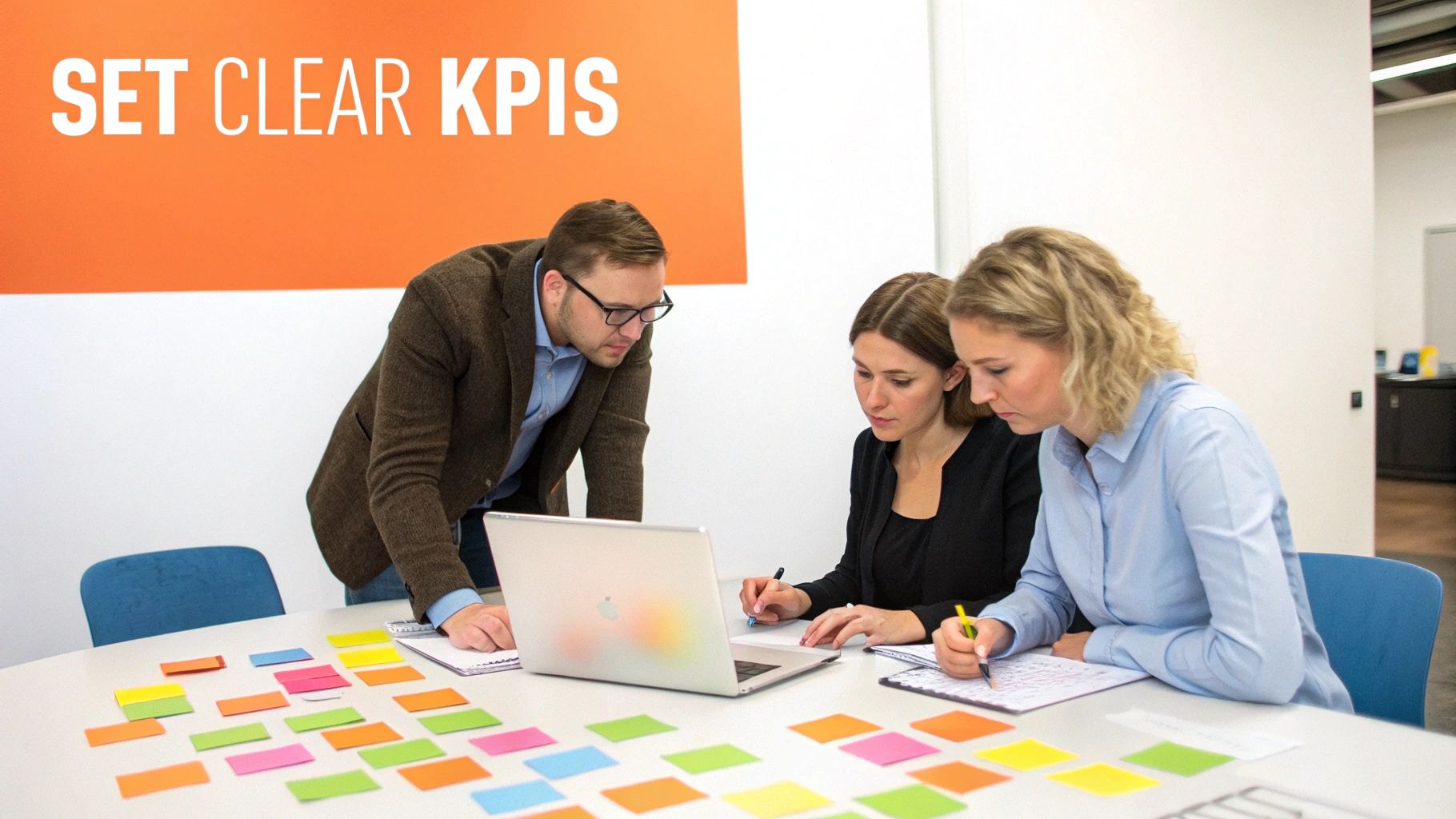 Three colleagues collaborate around a laptop and colorful sticky notes, planning strategies in an office.