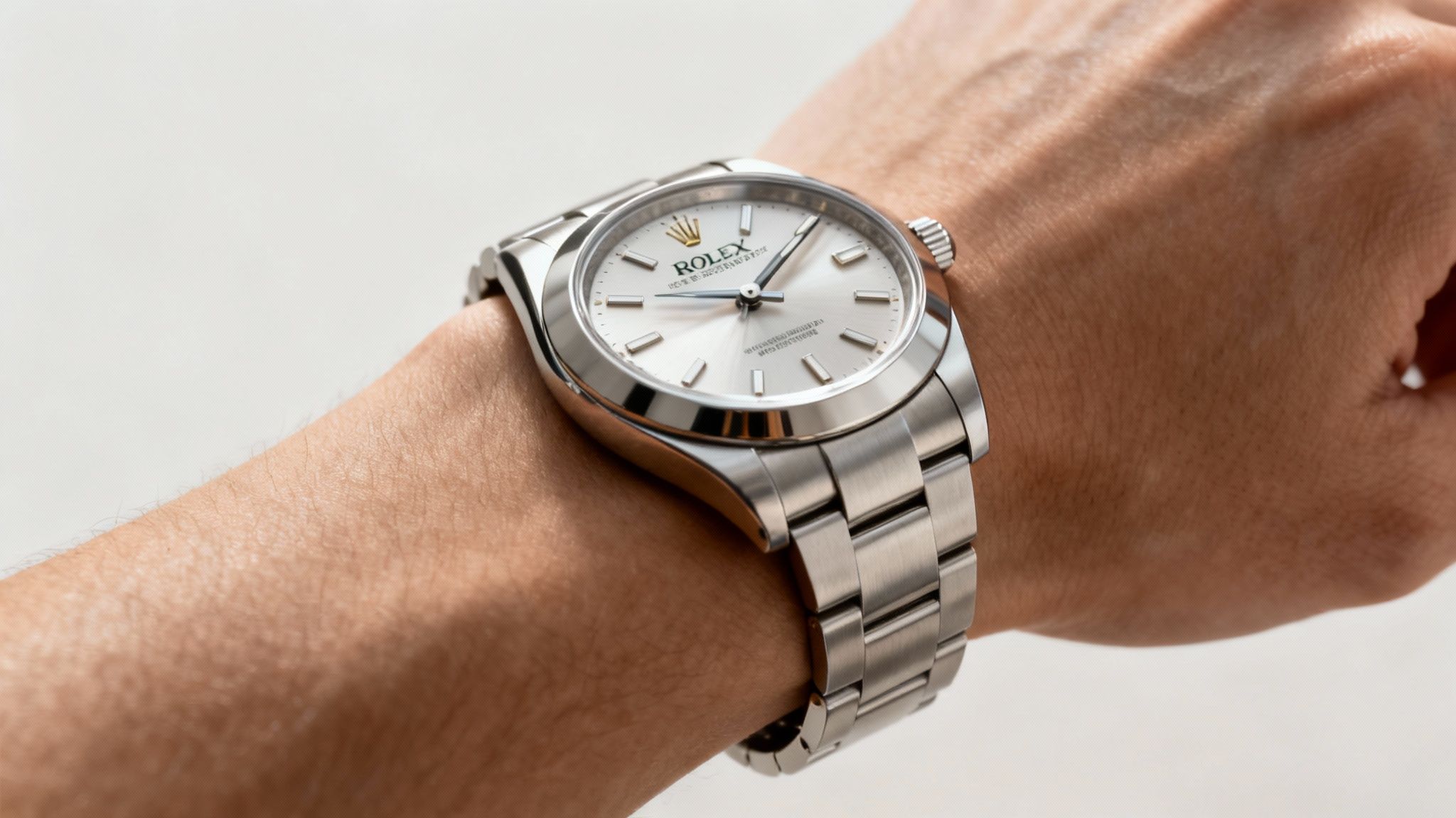 Close-up of a Rolex Oyster Perpetual watch with a silver band and white dial on a wrist.