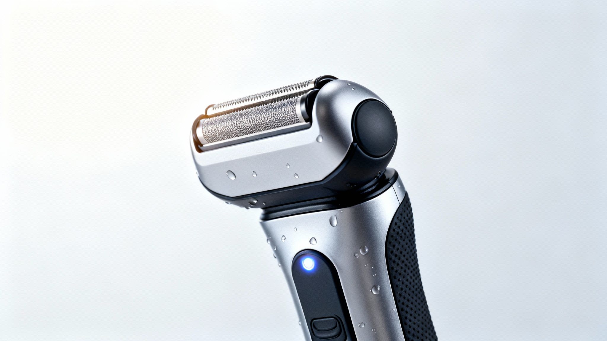 Detailaufnahme eines elektrischen Rasierers mit Wassertropfen und blau leuchtendem Indikator.